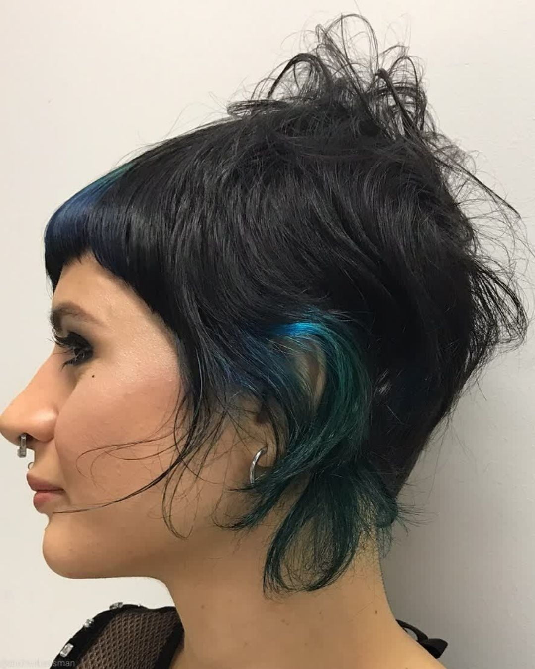 An angular bixie cut with blue detail on black hair.