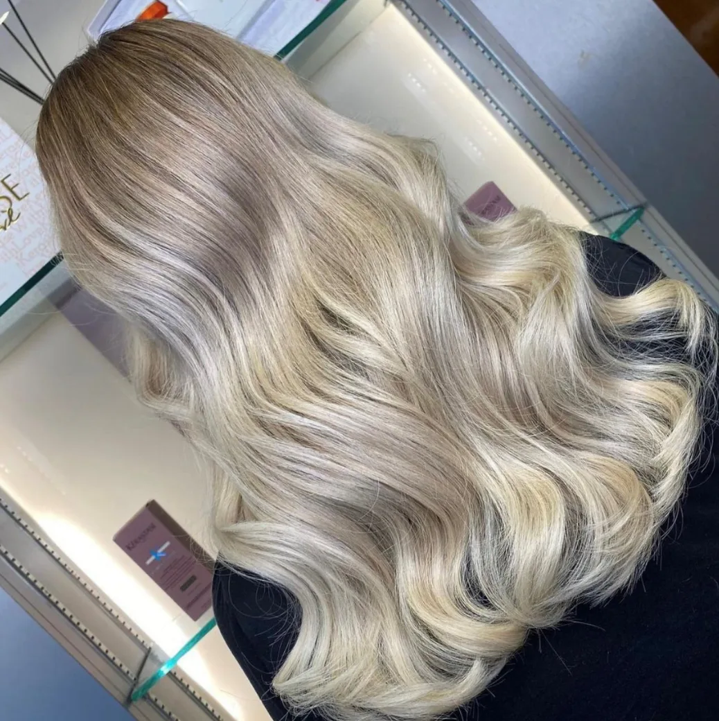 Back view of a woman with wavy blonde hair in front of cabinet with hair products